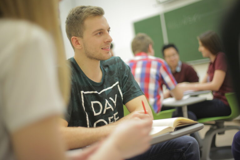 Group of young students is seating in the classroom and talking.